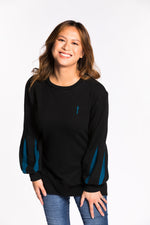 Chelsea wearing the Fighter Shield Pullover - Black/Teal. Chelsea is wearing an extra small. Her measurements are 36" Bust, 29" Waist, and 39" Hips, and she is 5'4".