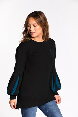 Chelsea wearing the Fighter Shield Pullover - Black/Teal. Chelsea is wearing an extra small. Her measurements are 36" Bust, 29" Waist, and 39" Hips, and she is 5'4".