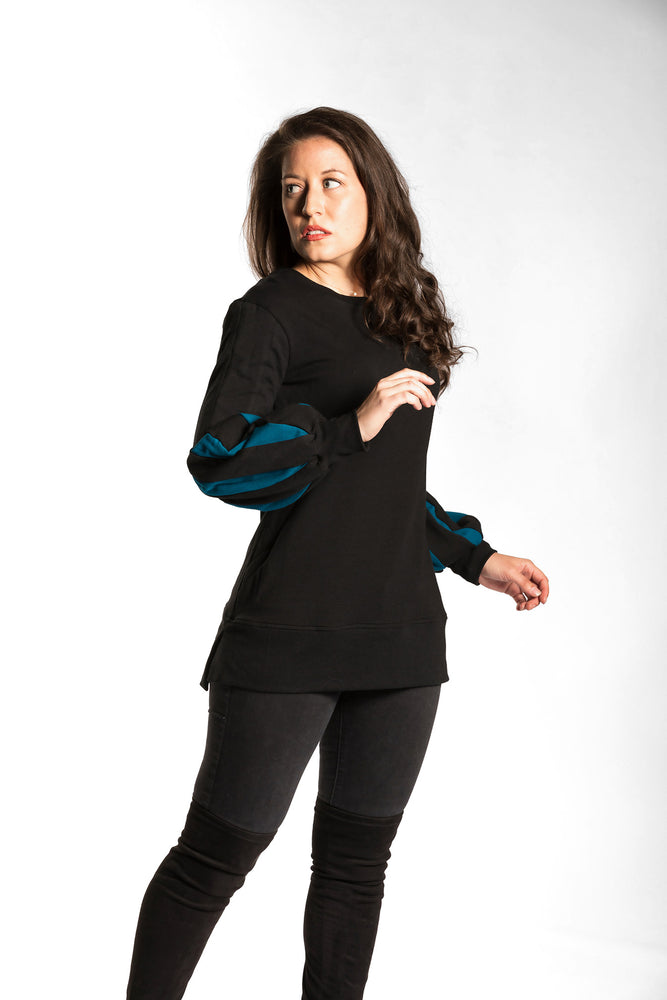 Victoria wearing the Fighter Shield Pullover - Black/Teal. Victoria is wearing an extra small. Her measurements are 34" Bust, 28" Waist, and 39" Hips, and she is 5'6"