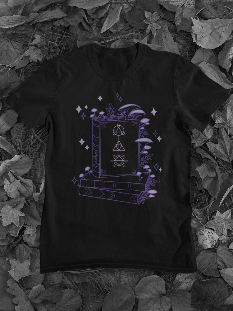 Close up of a mock-up of the Black x Purple Tone Wizard Floral Classic Tee. The design features an assortment of mushrooms decorating a pile of magical books..