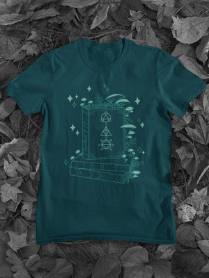 Close up of a mock-up of the Dark Teal Tone Wizard Floral Classic Tee. The design features an assortment of mushrooms decorating a pile of magical books..